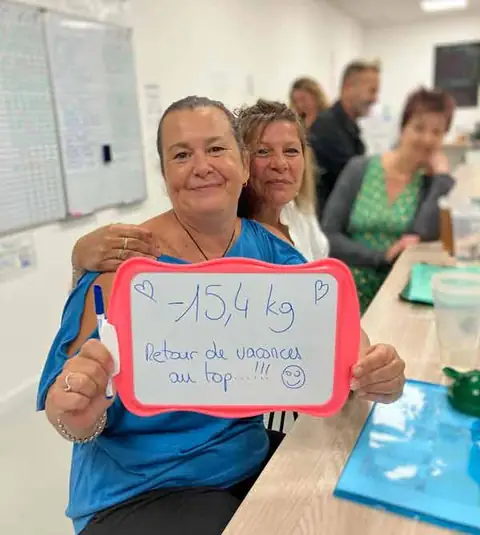 Au club, une membre souriante montre le bilan écrit sur son ardoise