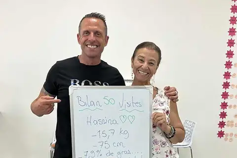 Un coach du club pose avec un membre et l’ardoise de son bilan